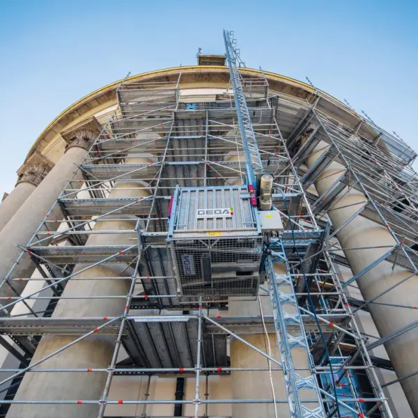 Das ist das perfekte Bild für das Thema Baustellen-Effizienz und Mitarbeiter-Entlastung (Gesundheitsschutz). Ein Bauaufzug wie der GEDA 500 ist nicht nur ein Transportmittel, er ist ein Produktivitäts-Booster. Für Dachdecker, Maler oder Fassadenbauer ist dieses Bild das Signal: „Gott sei Dank, bei Otto Wolf muss ich die Ziegel/Eimer nicht per Hand in den 4. Stock schleppen.“ Das macht euch auch als Arbeitgeber/Partner attraktiv. Hier sind die optimierten Texte für die Mediathek: Kopierfertige Inhalte für die Mediathek: Alternativer Text (Alt Text): "GEDA 500 Bauaufzug (Transportbühne) fachgerecht am Gerüst montiert – Effizienter Material- und Personentransport für Baustellen in Pforzheim