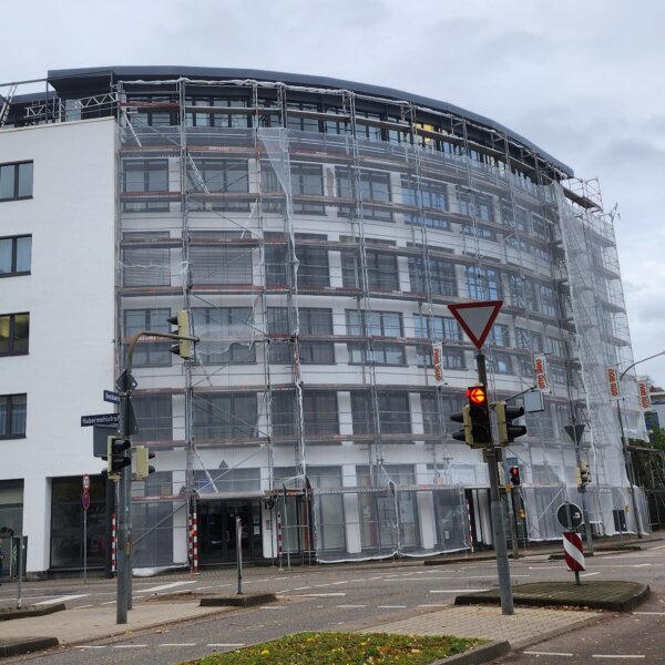 Komplett eingerüstetes Rundfassaden-Gebäude mit Staubschutznetz