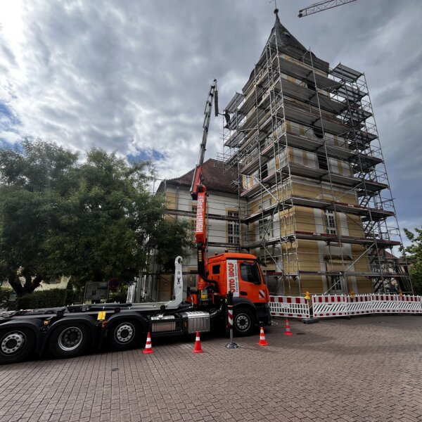 Kran hebt Gerüstmaterial an Kirchturmspitze